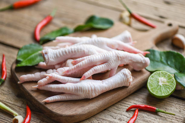 Fresh raw chicken feet for cooked food soup on the dark table kitchen background, Chicken feet on wooden cutting board with herbs and spices lemon chili garlic kaffir lime leaves