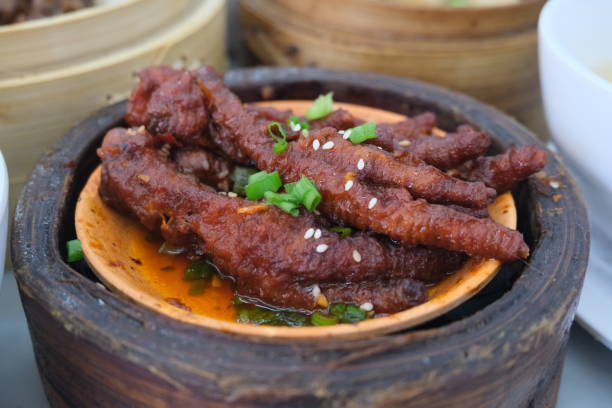 Authentic Chinese or Asian stewed chicken feet in a clay pot, garnished with green onions and sesame seeds for traditional menus